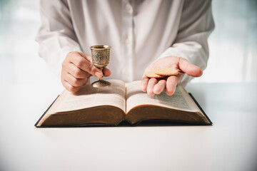 During the holy communion ceremony in church, a hand is extended in faith to receive the sacred...