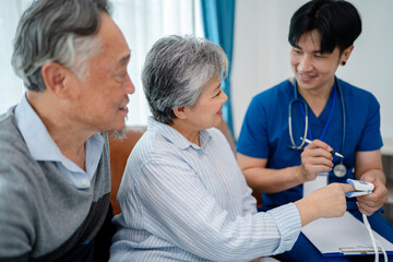 Obraz premium senior woman using pulse oximeter to measure blood oxygen instructed by physiotherapist. home caregiver nurse visit retire couple for health check up recovery process medical service