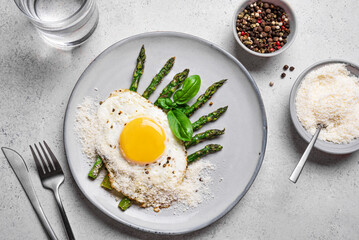 Fried egg with green asparagus and grated parmesan cheese for breakfast