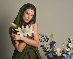 Close up portrait of beautiful brunette female model wearing green fantasy hooded cloak with crown...