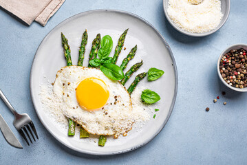 Fried egg with green asparagus and grated parmesan cheese for breakfast