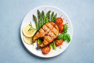 Grilled salmon steak with green asparagus, tomatoes and lemon slices