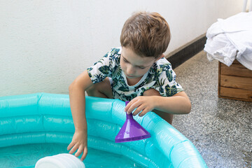 Little boy playing with toys near blue pool