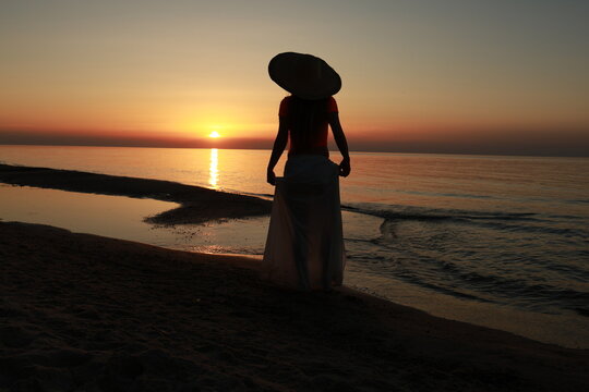 silhouette of woman walking on the beach at sunset