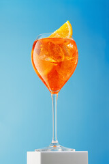 Misted glass of aperol spritz cocktail on blue background