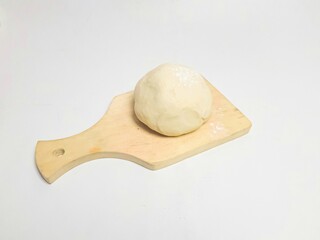 Soft, chewy cookie dough on a wooden board, isolated on a white background. Minimalist food concept.