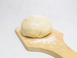 Soft and chewy floured cookie dough on a wooden board, isolated on a white background. Minimalist food concept.