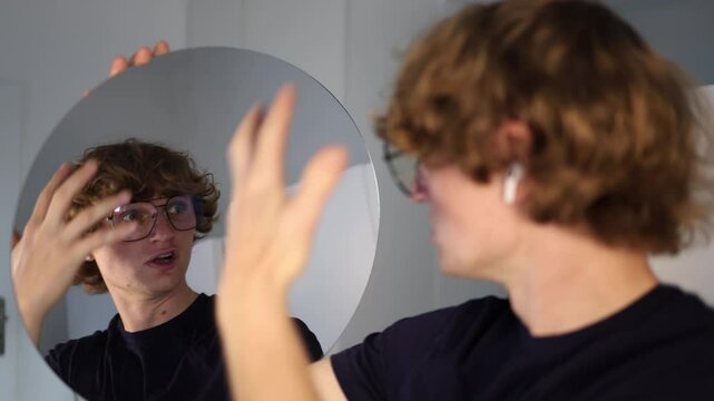 Young man touches his head while staring into the mirror with a tense face as if struck by a sudden genius idea that explodes in his mind with intense realization and mental spark