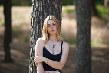 A young, beautiful blonde woman dressed in white trousers and a black cotton shirt leans her back...
