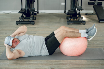 Man at the gym doing exercises for his abs with a Swiss ball