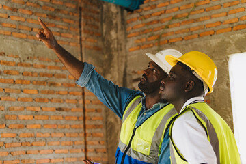 Two engineers in safety gear inspecting a building under construction. black engineers inspect ceiling infrastructure at a construction site