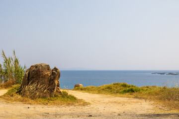 Large rock on dry coastal path with distant view of fish farm France, Corsica, Ajaccio, 13 June 2025