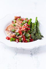 Grilled chicken fillet with asparagus and tomato salsa. Close up.	