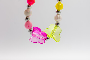 Bracelet with pink and yellow butterflies. The butterflies are made of clear plastic and are attached to a silver chain. The bracelet is colorful and playful.