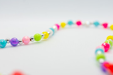Colorful necklace with many different colored beads. The beads are of various sizes and colors, and they are arranged in a line. The necklace appears to be made of glass beads, and it is a beautiful.