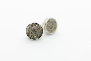 Pair of earrings with a diamond pattern. The earrings are silver and have a shiny appearance. They are sitting on a white background.