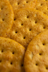 Savory golden crackers arranged closely, showcasing their texture and detail under warm lighting, perfect for snacking during gatherings or parties