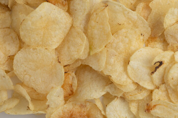Crispy potato chips scattered on a white surface ready for snacking during a casual gathering or...