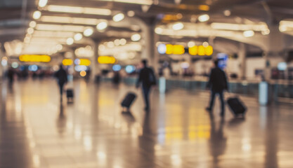 Blurred airport scene with people pulling luggage on a shiny floor.