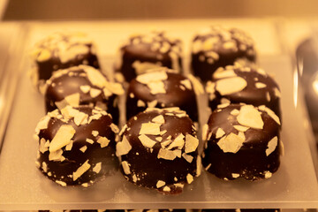 Handcrafted chocolate truffles topped with crushed nuts displayed in a confectionery shop during afternoon