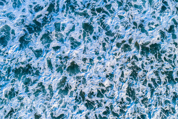 aerial top down abstract of vibrant blue ocean water covered in white foam, aerial drone view