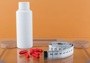 Red capsules, White bottle of dietary supplements next to a measuring tape.