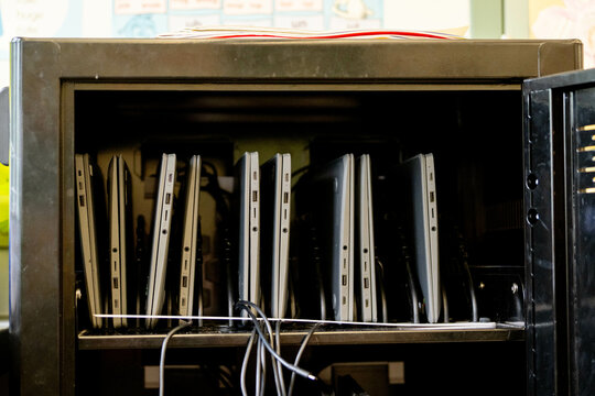 Laptop charging cart in an elementary school classroom with organized portable computers for classroom technology management and digital learning.