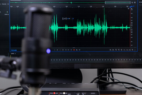 Studio microphone and monitor displaying green audio waveform for professional sound recording, podcast creation, and digital content