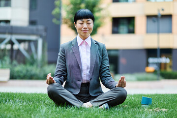 Portrait of a young asian japanese businesswoman woman practicing yoga outdoors, surrounded by...