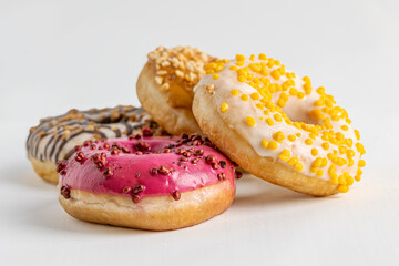 assorted glazed freshly baked donuts on white surface close up