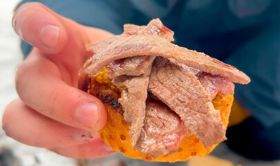 Bruschetta with marbled beef and Dijon mustard in hand, close-up