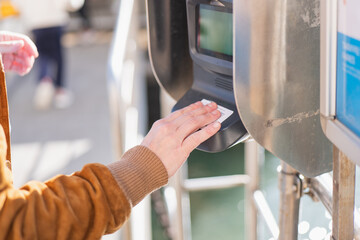 Touching a transit card at a ticket kiosk near the waterfront in bright daylight
