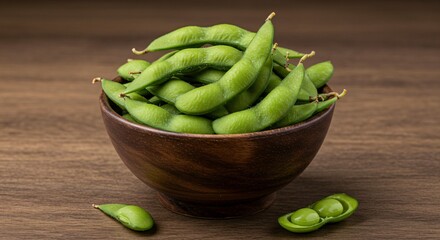 A wooden bowl filled with fresh green edamame pods on a brown wooden surface in a studio setting