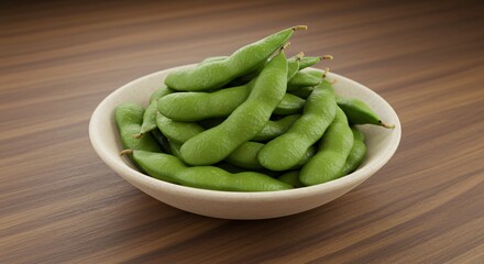 A close up of a white bowl filled with fresh green edamame pods on a wooden surface background view