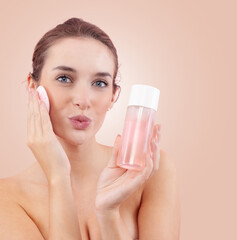 Portrait of young woman removing makeup with cotton pad, blowing kiss to camera and holding...