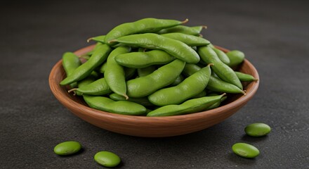 A wooden bowl filled with fresh green edamame pods sitting on a dark gray surface in a close up view