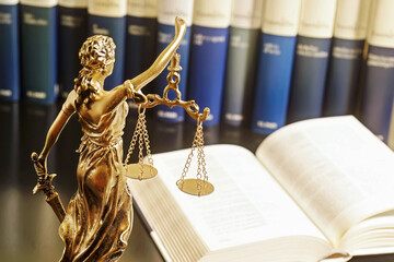 statue Themis representing justice and fairness  with law books to consulting , focus  in foreground