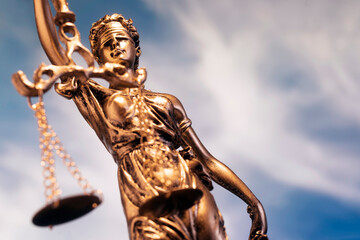 statue Themis representing justice and fairness with blue sky with clouds unfocused in background