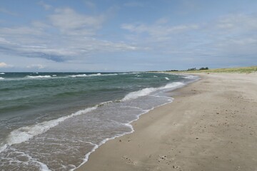 Wellen branden am Strand des Ostseebads Dierhagen auf dem Fischland. Es ist ein stürmischer Sommertag. Im Hintergrund sind Dünen mit Strandhafer zu sehen.