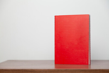 A red book on a wooden table. Book concept. Knowledge concept. 
Space for text.