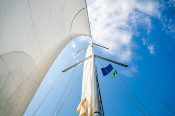 Fototapeta premium White sails filled with wind, seen from the bow of a sailing yacht near Croatia. Freedom, clean energy, adventure and mindful travel on the open sea.