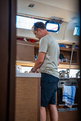 Man cooking in the galley of a sailing yacht near Croatia. Life on a boat, independence, minimalism...