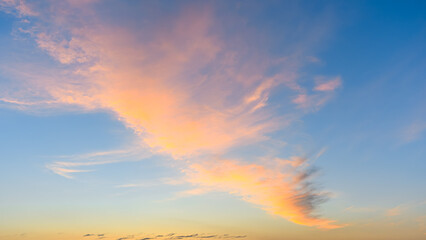 Light pink clouds float near the horizon under a clear blue morning sky during early sunrise.