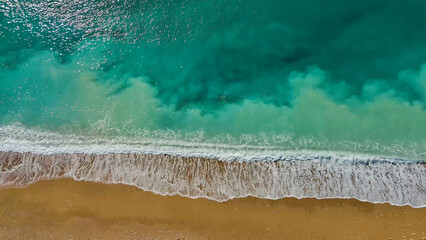 Turquoise water and sea waves on a yellow sand.