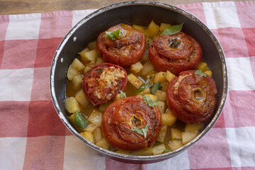baked stuffed tomatoes with rice and potatoes in a pan