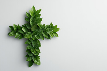 Fresh green leaves arranged in the shape of a medical cross symbolize natural medicine, healthcare, and environmental awareness, set against a clean white background with copy space