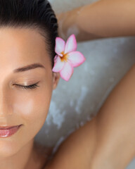 Half Face Close-Up of Relaxed Woman With Flower in Hair During Spa Bath Session