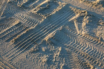 close-up of various tire tracks in the sand on the beach