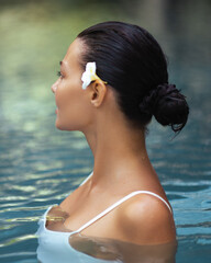 Elegant Woman in Profile Relaxing in Pool with Tropical Flower in Hair