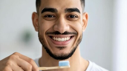 Handsome man smiling showing teeth holding a toothbrush ready for brushing, concept for healthy teeth, dental care, and hygiene.